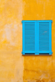 Blue shutter on yellow plaster wall