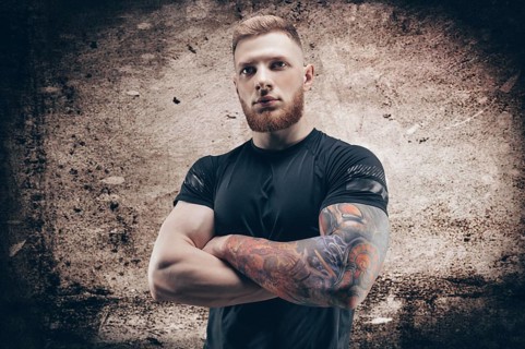 Young muscular guy posing against the background of a concrete wall. Fitness and nutrition concept.