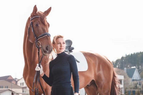 Beautiful stylish woman walking with a horse in a country club. Equestrian sport