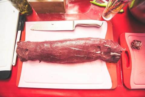A piece of meat is marinated and prepared for grilling