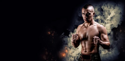 Portrait of a boxer of mixed martial arts standing on the background of smoke and fire. The concept of sports
