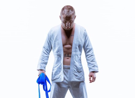 Athlete in a kimono with a blue belt stands with his head down. The concept of karate and judo.