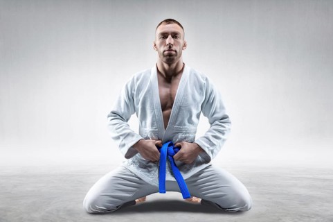 Athlete in a kimono with a blue belt sits and waits for the opponent. Concept of karate