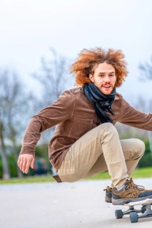 Vertical photo with copy space of a happy young man skateboarding in a park