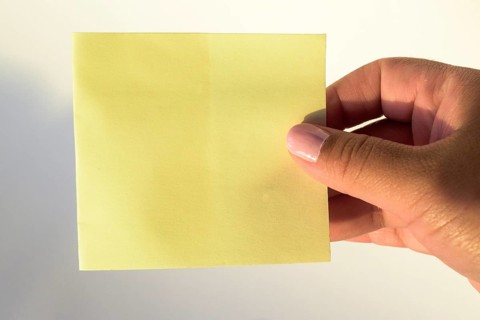 Woman's hand with painted nails holding blank letter paper on pure white background