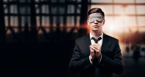 Man in a business suit and a mask for sleeping is standing at the airport. He is praying. Airline concept. Caring for passengers.