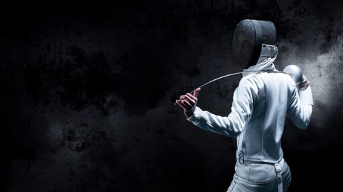 Charming girl dressed as a fencer posing with a mask and a sword. The concept of fencing. Back view.