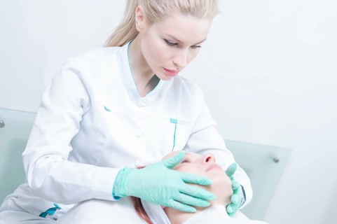 Doctor in a dressing gown examines the patient's face. Plastic surgery concept.