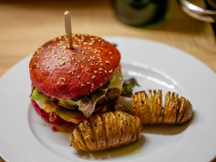 Delicious veggie burger in a beetroot bun with sliced potatoes