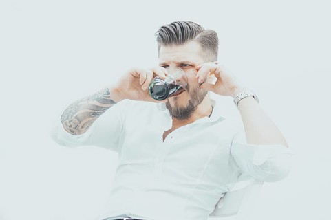 Stylish man sits on a chair and gets drunk with rum and cola. The concept of unsuccessful business