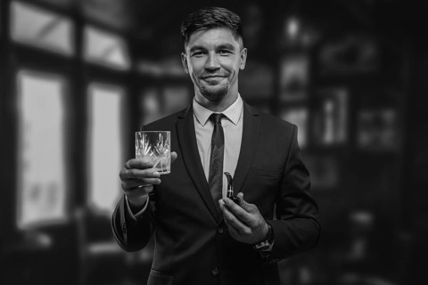 Portrait of an elegant man in a suit with a smoking pipe and a glass in a restaurant. Business concept.