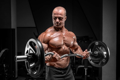 Professional weightlifter posing in the gym with a barbell in his hands. Classic bodybuilding.