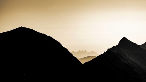 Mountain ridge with mountaineers and Swiss mountains and Lake Thun in the background at sunrise