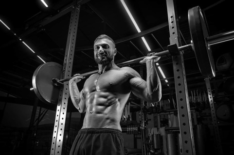 Muscular man posing in the gym with a barbell. Fitness concept.