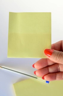 Woman's hand with painted nails holding blank letter paper on pure white background