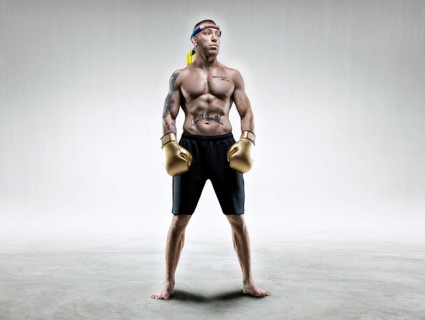 Professional wrestler is standing in a bright room. Mixed martial arts