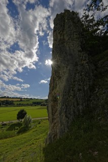 Striking limestone rock formation Burgstein with blue and white sky in the upper Altmuehltal surrounded by green vegetation