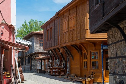 View into an alley with traditional wooden buildings and souvenir shops under a clear blue sky