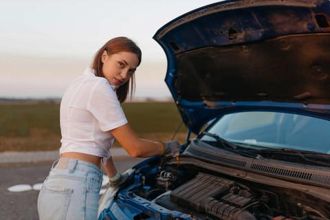 Young beautiful hot girl driver checks oil level