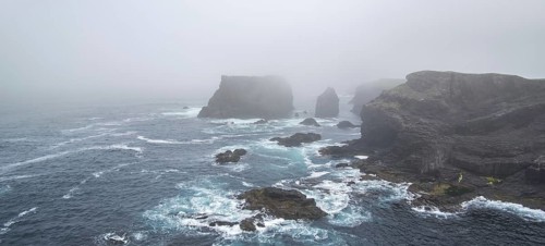 Sea stacks and sea cliffs in mist during stormy weather at Eshaness