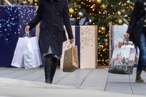 Christmas shopping at Outletcity Metzingen. Consumer tourists lug shopping bags. Factory outlet with around 80 shops of premium and luxury brands specialising in clothing