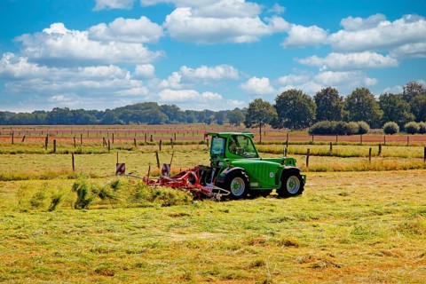 A farmer with his tractor and hay tedder