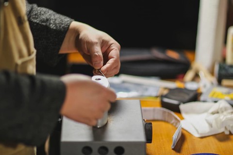 Unrecognizable luthier lute maker artisan both hands performing bend controller purfling strips process in iron tool for a new raw back and front plates of classic handmade violin in his workshop in C...