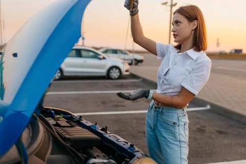 Young beautiful hot girl driver checks oil level