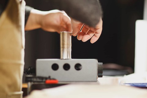 Unrecognizable luthier lute maker artisan both hands performing bend controller purfling strips process in iron tool for a new raw back and front plates of classic handmade violin in his workshop in C...