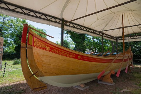 Traditional wooden boat under a white tent on a sunny day with green surroundings