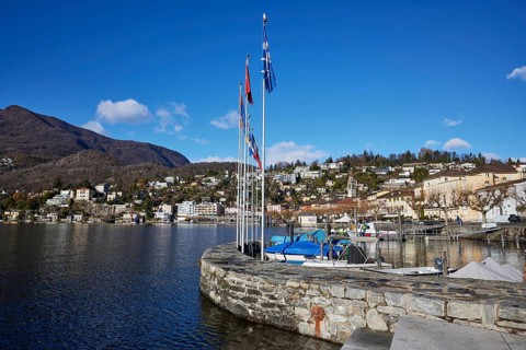 Harbour with flags and stone wall in Ascona