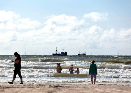 Family bathing with children on a North Sea fishing boat beach