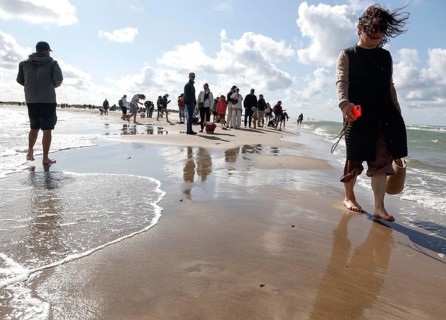 Tourists stand with one foot in the North Sea and one in the Baltic Sea in Grenen or Skagens Gren