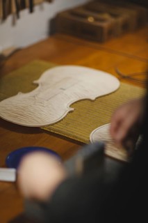 Unrecognizable luthier lute maker artisan in his workshop performing purfling process in a new raw classic handmade violin