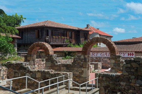 View of a traditional house behind old brick arches under a sunny sky