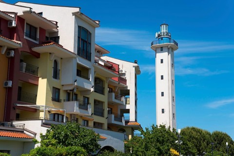 White lighthouse at a hotel complex under a clear blue sky