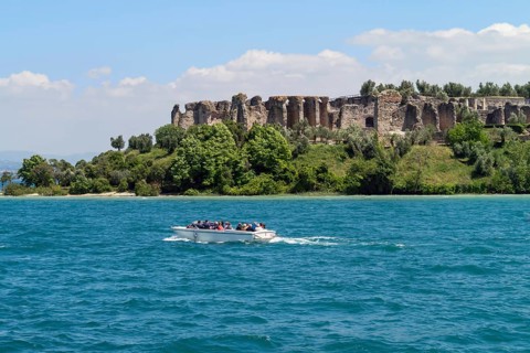 Boat with tourists in front of the Grottoes of Catullus