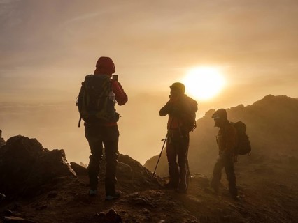 Mountaineer taking photos with his mobile phone in the fog at sunrise