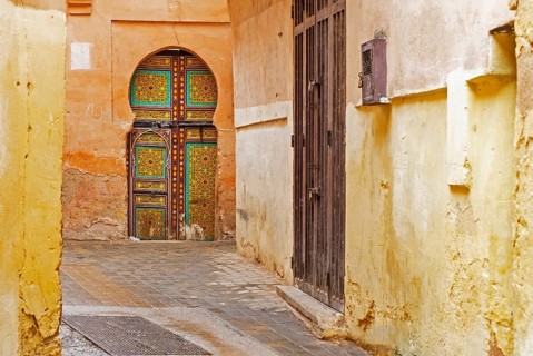 Moorish decorated door in alley of the old historic yellow medina of the city Meknes