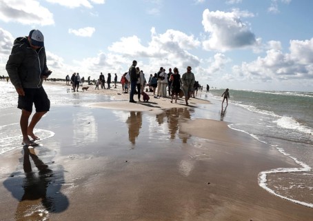 Tourists stand with one foot in the North Sea and one in the Baltic Sea in Grenen or Skagens Gren