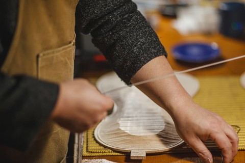 Unrecognizable luthier lute maker artisan both hands performing bend controller purfling strips process in iron tool for a new raw back and front plates of classic handmade violin in his workshop in C...