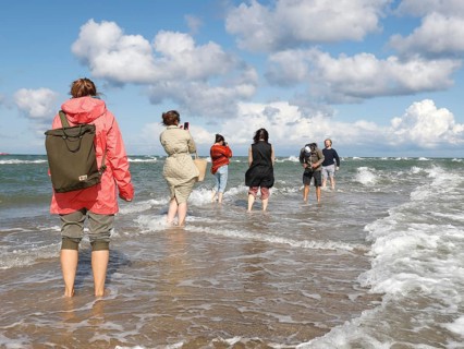 Tourists stand with one foot in the North Sea and one in the Baltic Sea in Grenen or Skagens Gren