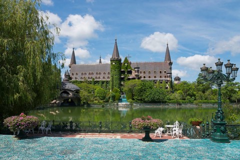 A picturesque castle with turrets is reflected in a tranquil lake
