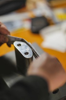 Unrecognizable luthier lute maker artisan hands in his workshop performing bend controller purfling strips process in iron tool for a new raw back and front plates of classic handmade violin in Cremon...