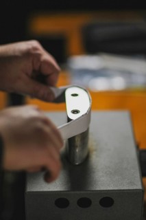 Unrecognizable luthier lute maker artisan both hands performing bend controller purfling strips process in iron tool for a new raw back and front plates of classic handmade violin in his workshop in C...