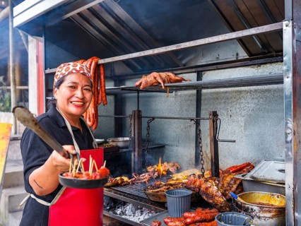 Woman at a street barbecue with lots of meat and sausage