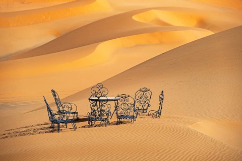 Cast iron garden table and lawn chairs in sand dunes of Erg Chebbi in the Sahara Desert near Merzouga
