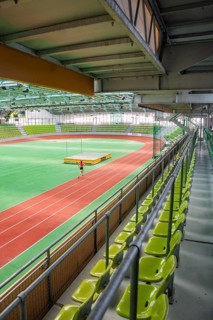 Athlete training on the running track in a stadium with green rows of seats