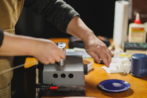 Unrecognizable luthier lute maker artisan both hands performing bend controller purfling strips process in iron tool for a new raw back and front plates of classic handmade violin in his workshop in C...