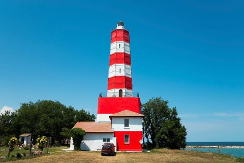 Red and white striped lighthouse on a sunny day with a clear blue sky and calm sea